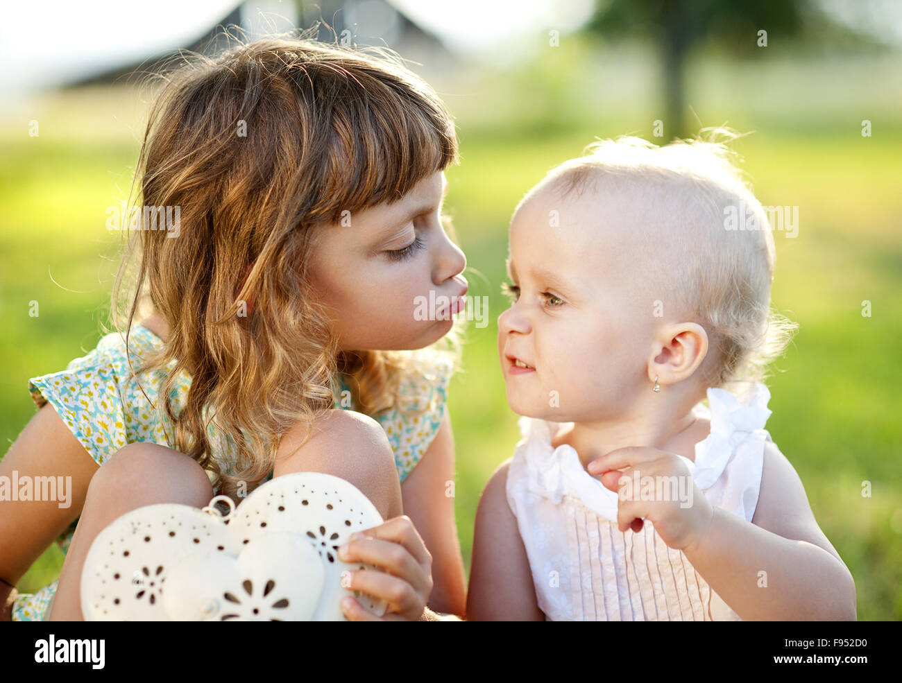 Due graziosi Piccole sorelle di ridere e giocare nel verde parco di sole Foto Stock