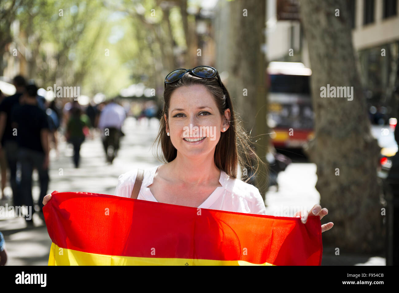 Donna felice turistico è camminare nella via della città di Barcelon con bandiera spagnola. Foto Stock