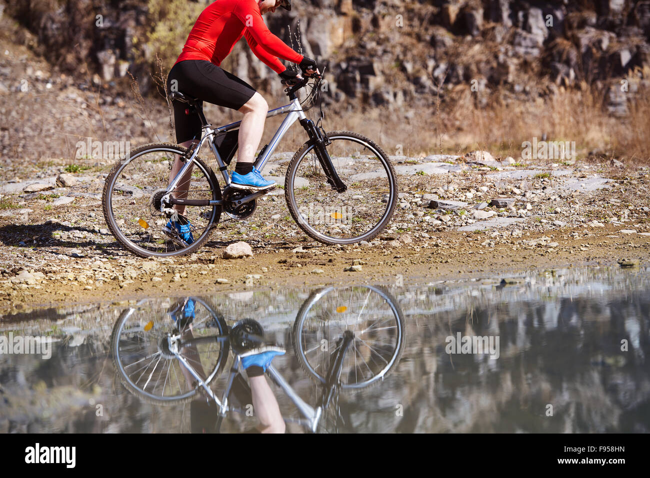 Dettaglio del ciclista uomo riflettendo in pozza d'acqua Foto Stock