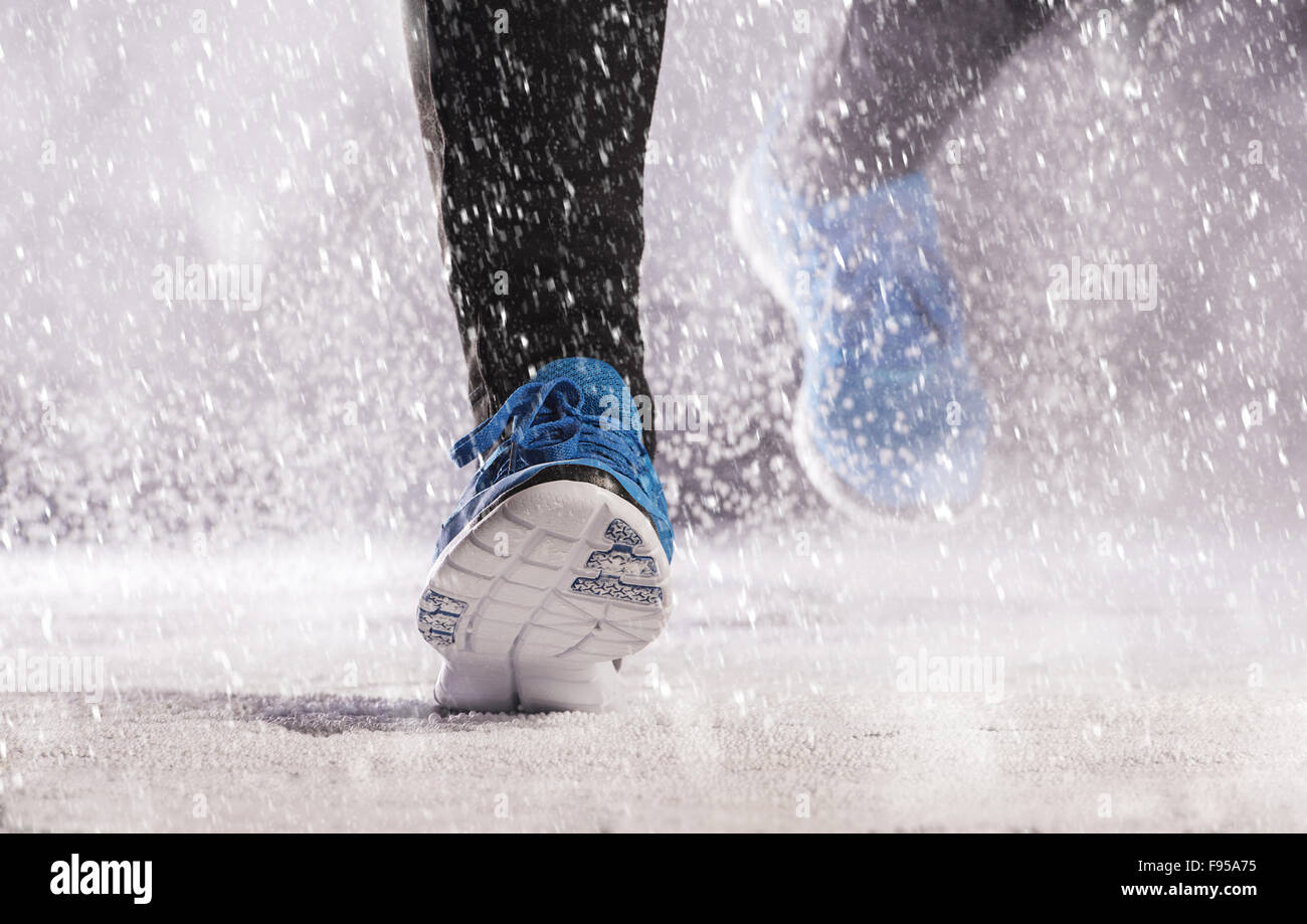 Atleta donna è in esecuzione durante gli allenamenti invernali al di fuori nella neve fredda meteo. Foto Stock