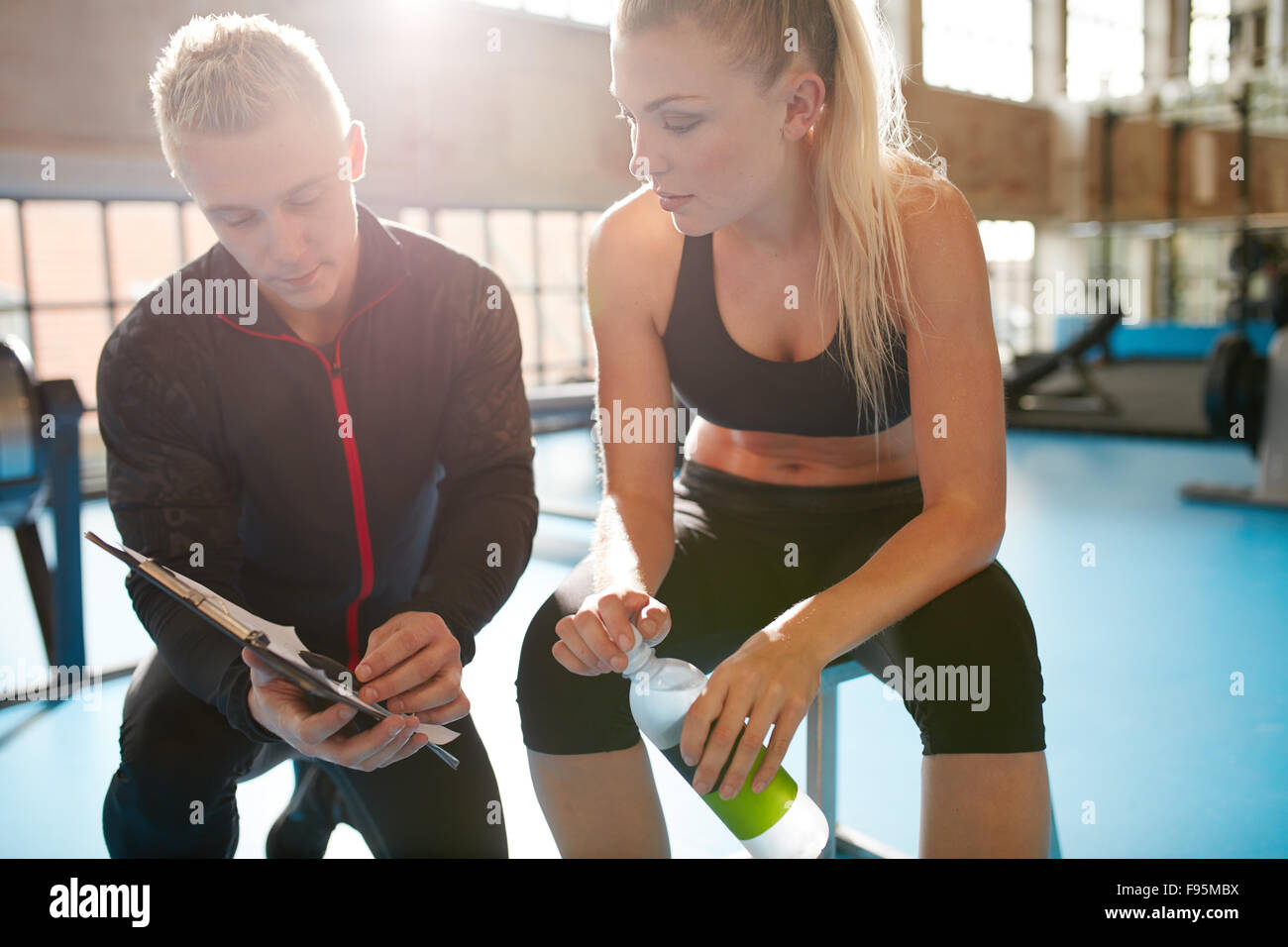 Inquadratura di un personal trainer aiutando una palestra gli stati con il suo piano di esercizio. Trainer passa attraverso il piano di fitness con client in hea Foto Stock