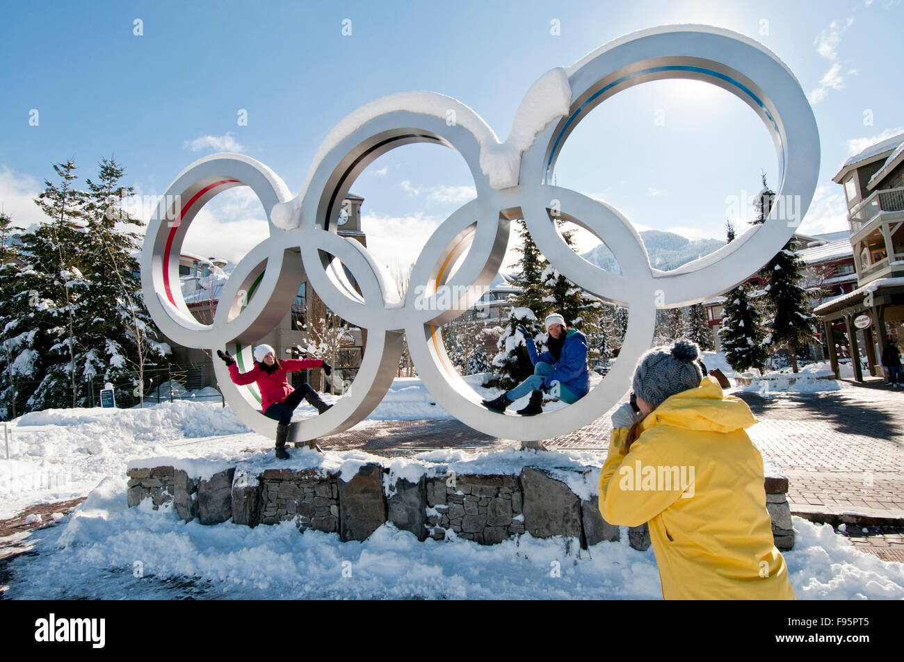 Un trio di donne di scattare foto a gli anelli olimpici nel villaggio di Whistler in un giorno d'inverno. Foto Stock