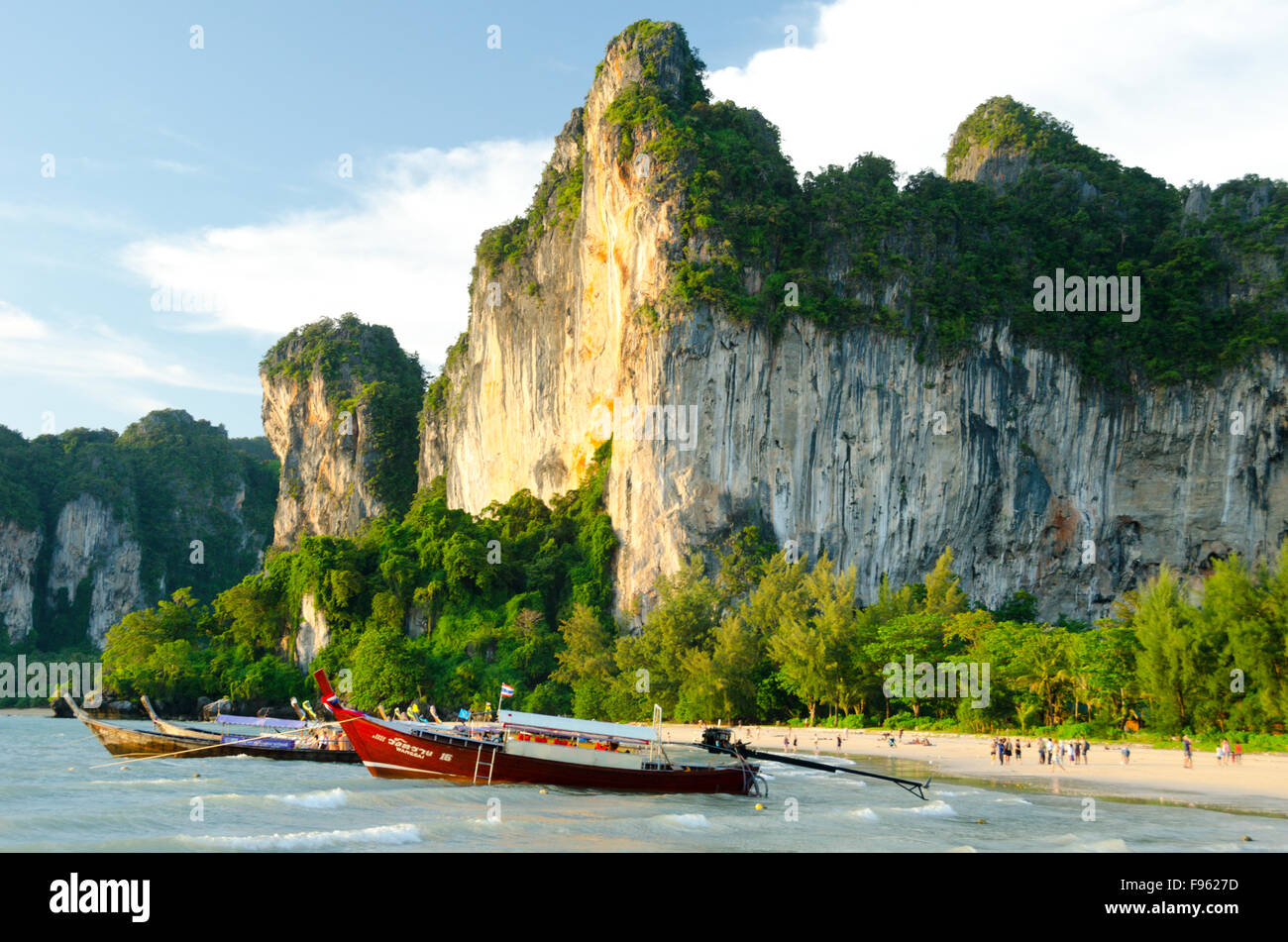 Longtailed barche ormeggiate a Railay Beach, Thailandia, mentre i turisti passeggiare al tramonto Foto Stock