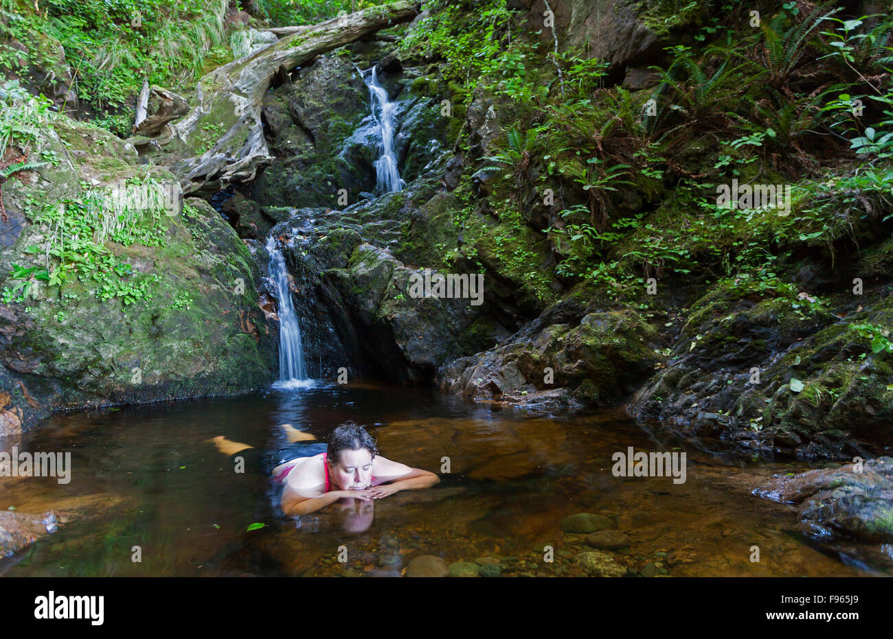Una donna matura si rilassa in una piscina di acqua fresca dopo escursioni a San Josef Bay. San Josef Bay,l'isola di Vancouver, British Foto Stock