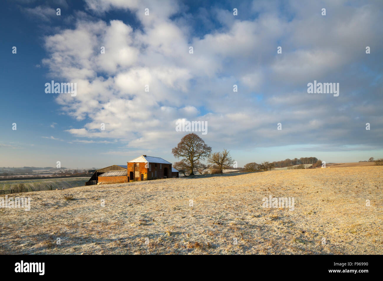 Abbandonata la vecchia casa colonica con stalla moderna accanto ad esso, in un paesaggio invernale dopo l'alba, East Haddon, Northamptonshire, Inghilterra Foto Stock