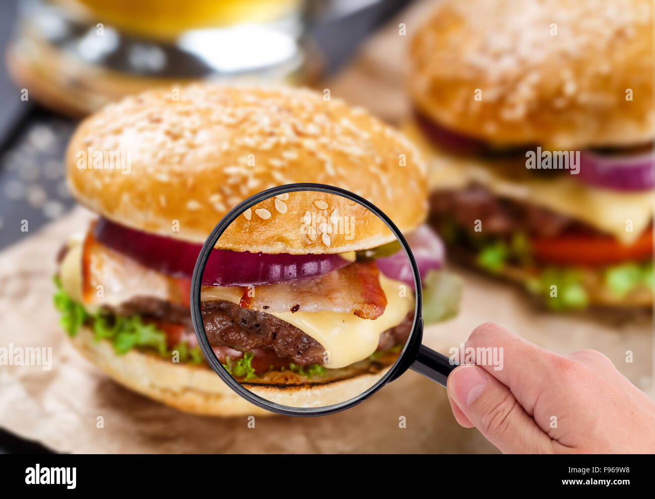 Lente di ingrandimento esaminando burger Foto Stock