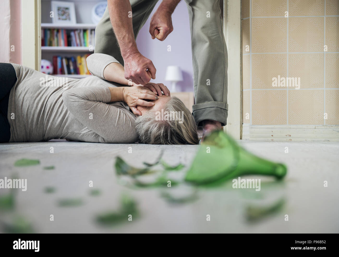 La donna vittima di violenza domestica e abusi. Donna matura la paura di un uomo con bottiglia rotta Foto Stock