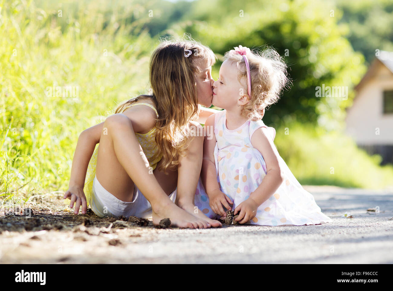 Due graziosi piccole sorelle sittting e baciare in natura Foto Stock