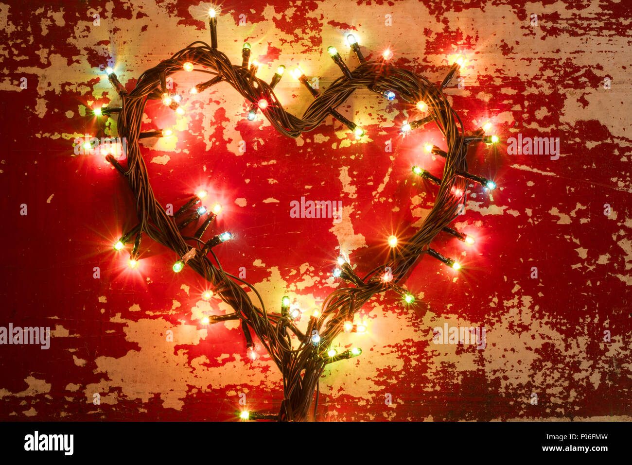 Concetto di vacanza, amore composizione con forma di cuore fatta da luci di Natale su grunge texture di legno dello sfondo. Foto Stock