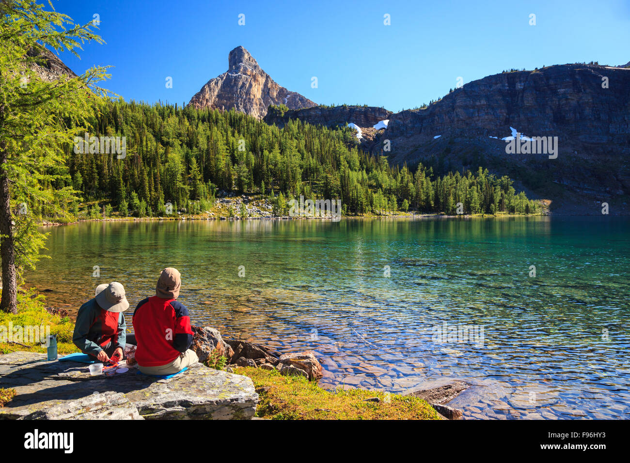 Due escursionisti prendere una pausa pranzo sulla riva del lago di scarabeo, il Parco Nazionale di Banff, Alberta, Canada, Modello rilasciato. Foto Stock