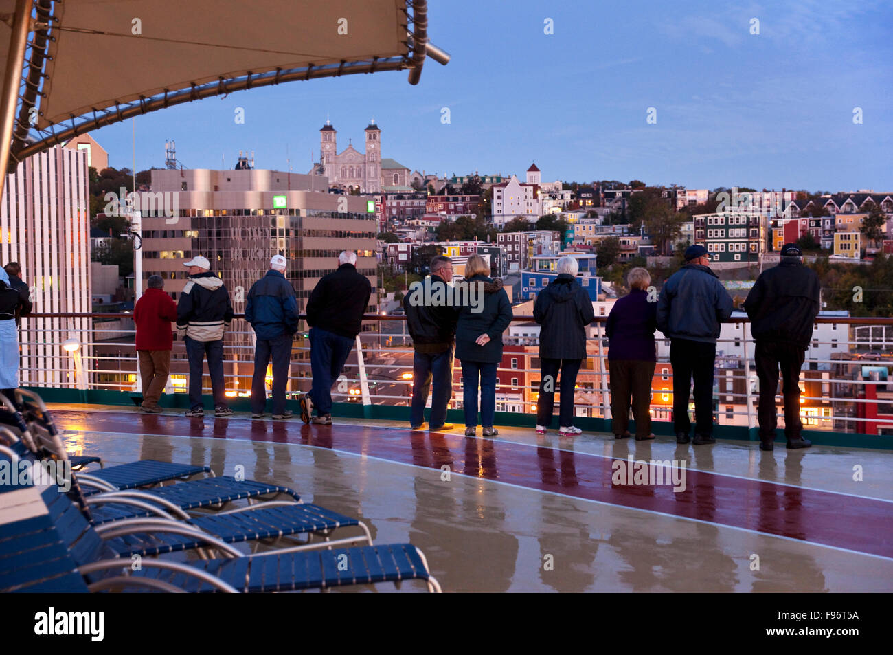 Come la loro nave da crociera inizia le manovre di attracco, una fila di passeggeri sguardo sulla città di St. Johns, Terranova, all'inizio Foto Stock