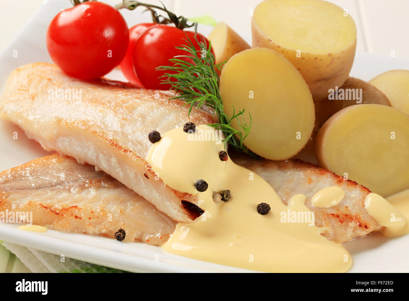 White i filetti di pesce con patate e salsa olandese Foto Stock