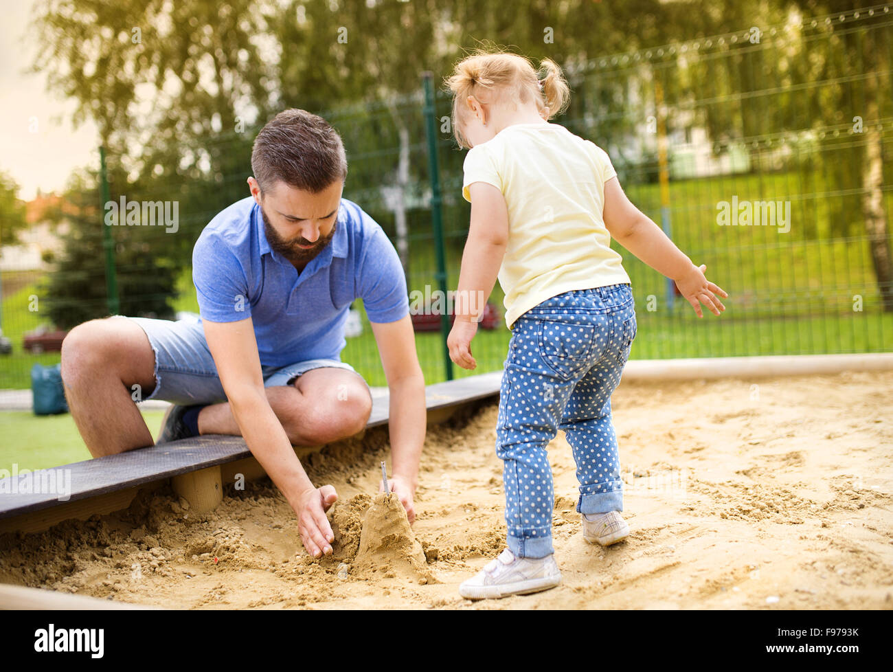 Padre sorridente e la sua piccola figlia giocando sul parco giochi. Foto Stock