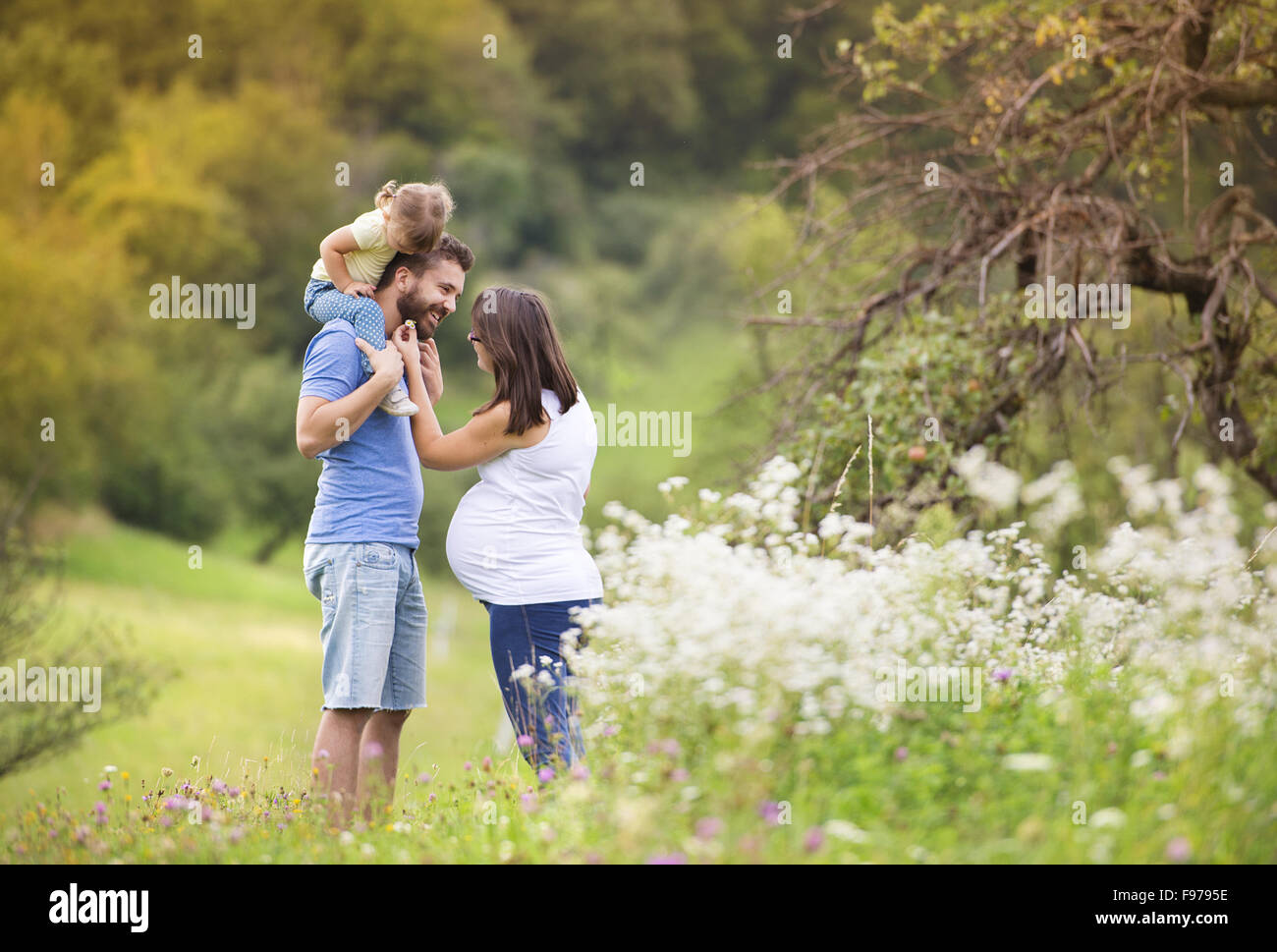 Felice famiglia incinta avendo divertimento in estate la natura Foto Stock