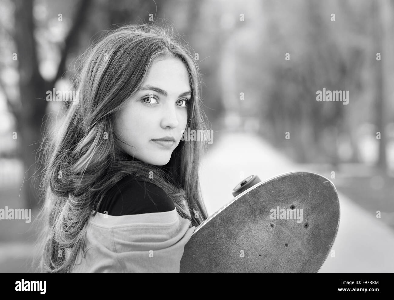 Bianco e nero ritratto della bella ragazza adolescente con lo skateboard in parco verde Foto Stock