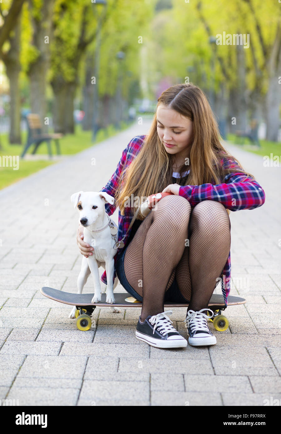 Ragazza adolescente su skateboard con il suo cane Foto Stock