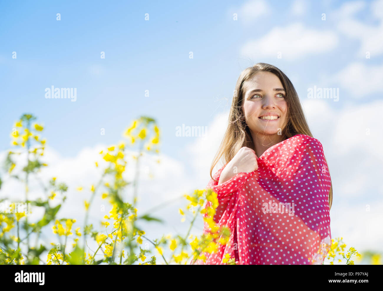 Felice ragazza giovane con la sciarpa rossa godendo del tempo libero in giallo campo di colza Foto Stock