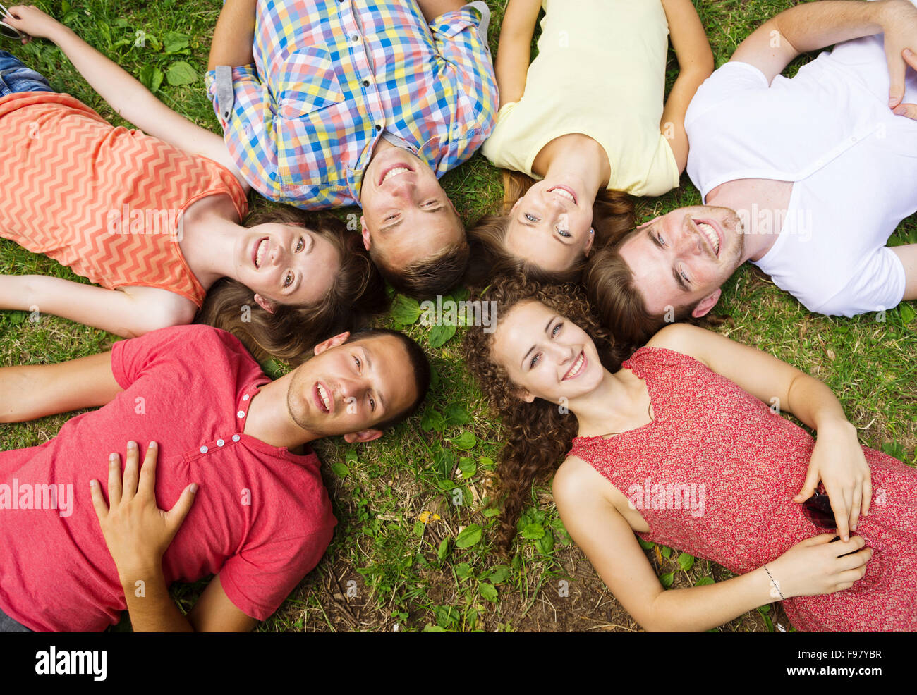 Gruppo di giovani si divertono nel parco, sdraiati sull'erba Foto Stock