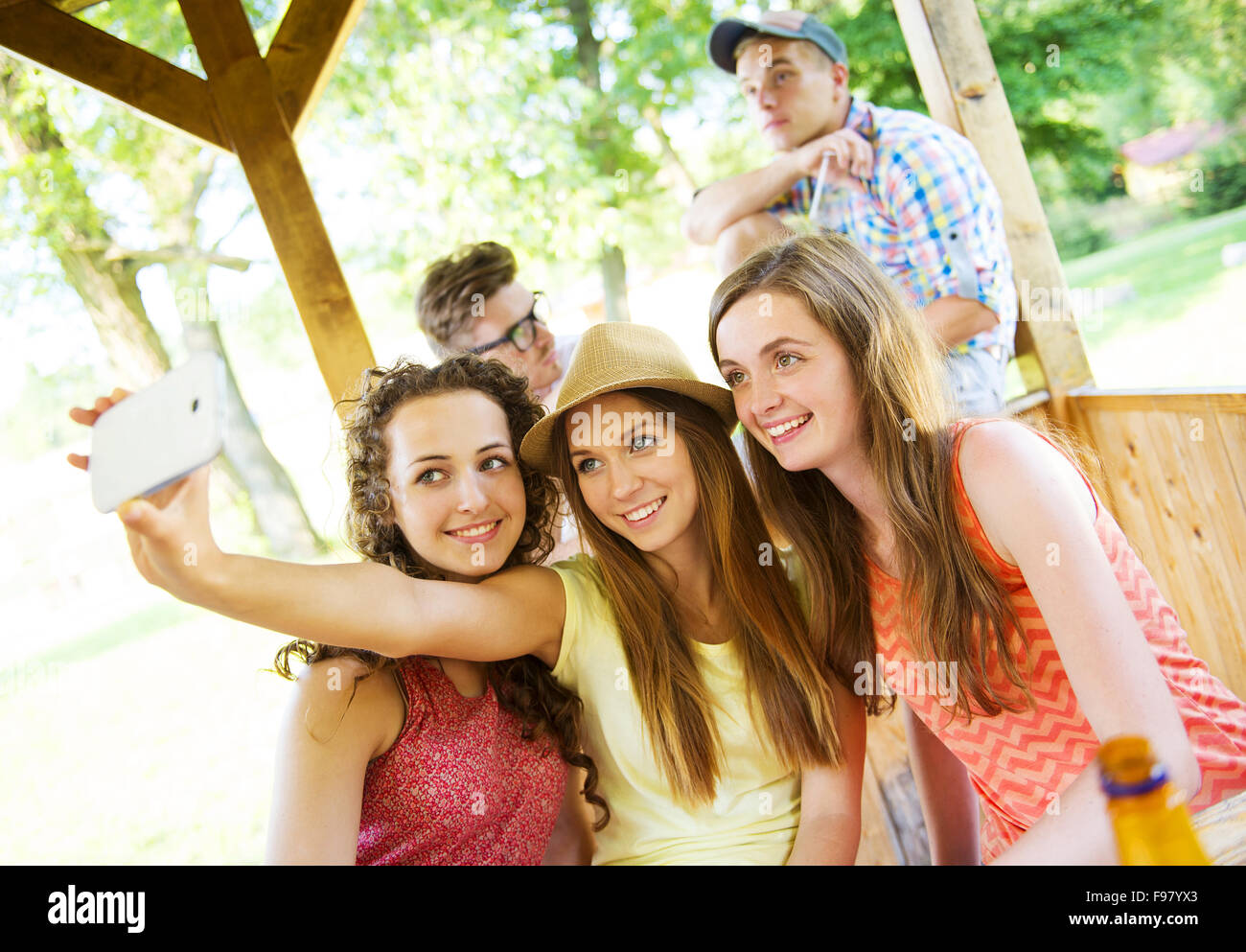 Tre belle ragazze bere e tenendo selfie con lo smartphone in pub garden Foto Stock