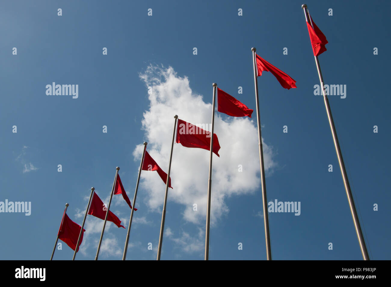 Linea di bandiere rosse di fronte nuvoloso cielo blu a Kashgar cina Foto Stock