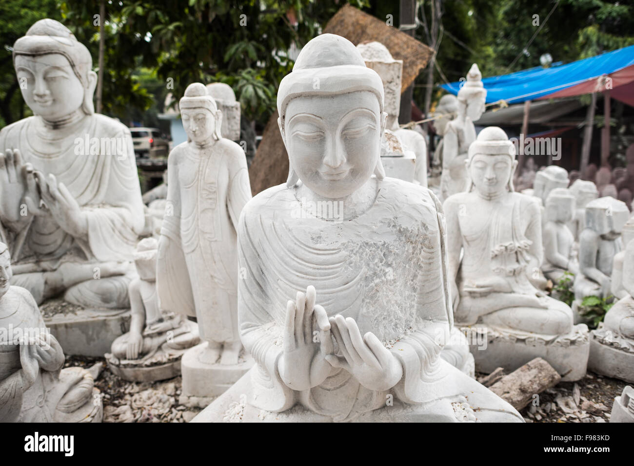 MANDALAY, Myanmar - gli artigiani locali intraprendono il lavoro polveroso e sfrenato di intagliare statue del Buddha in marmo. Poiché il buddismo è la religione dominante in Myanmar, c'è una notevole domanda di statue, con i clienti in grado di scegliere tra una miriade di pose, dimensioni e stili. Gli artigiani sono raggruppati in una strada nel quartiere Chanmyathazi di Mandalay vicino alla Pagoda Mahamuni. Foto Stock