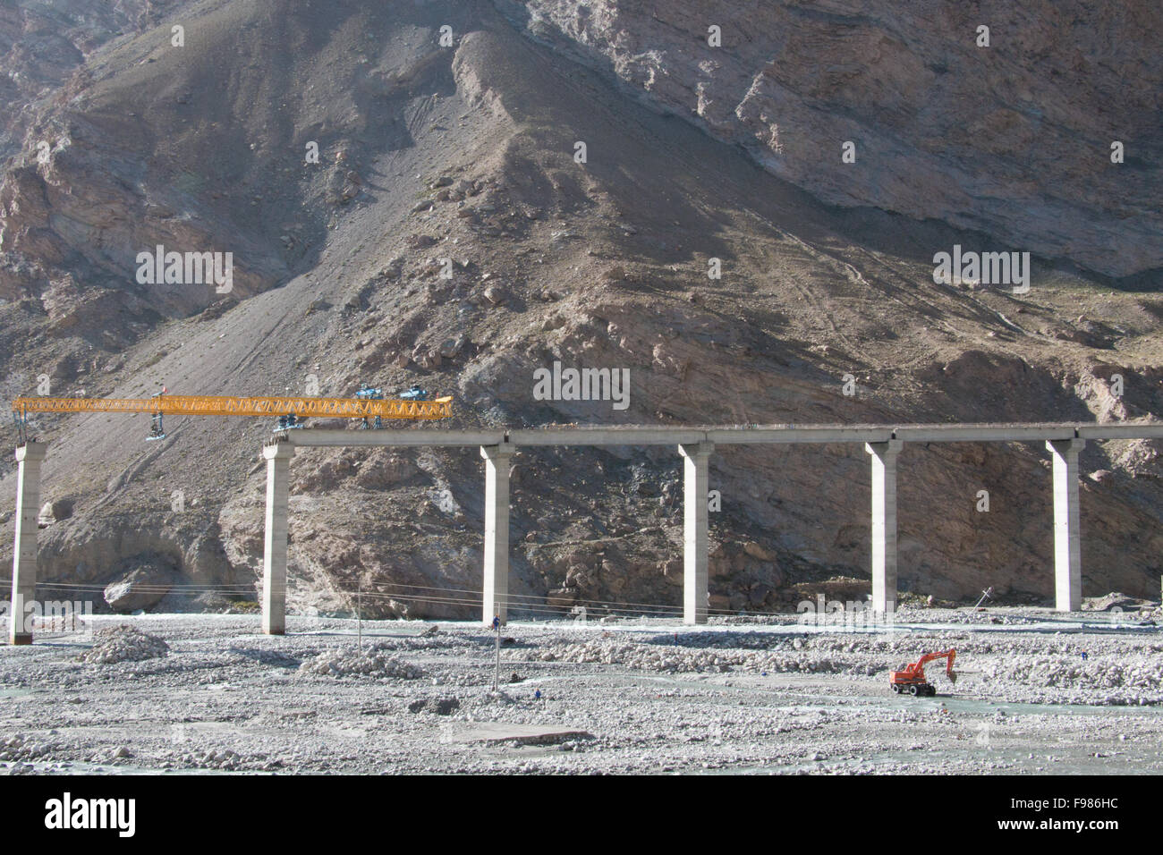 Strada in costruzione in una vasta zona di montagna con un unico escavatore Foto Stock