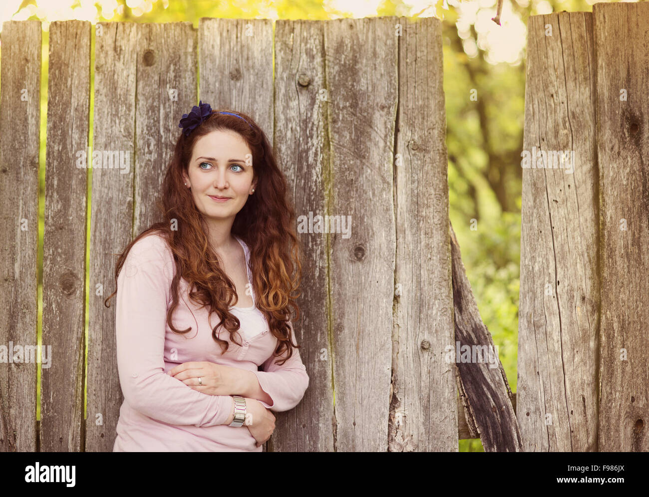 Bella bruna donna in piedi dalla vecchia recinzione di legno Foto Stock