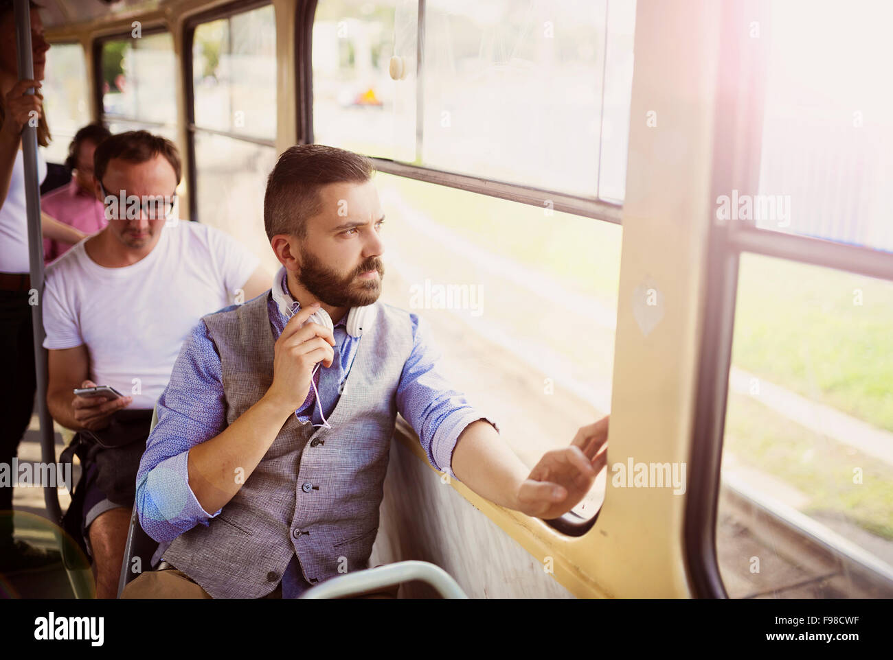 Bello hipster l uomo moderno con cuffie di viaggiare in tram in città Foto Stock