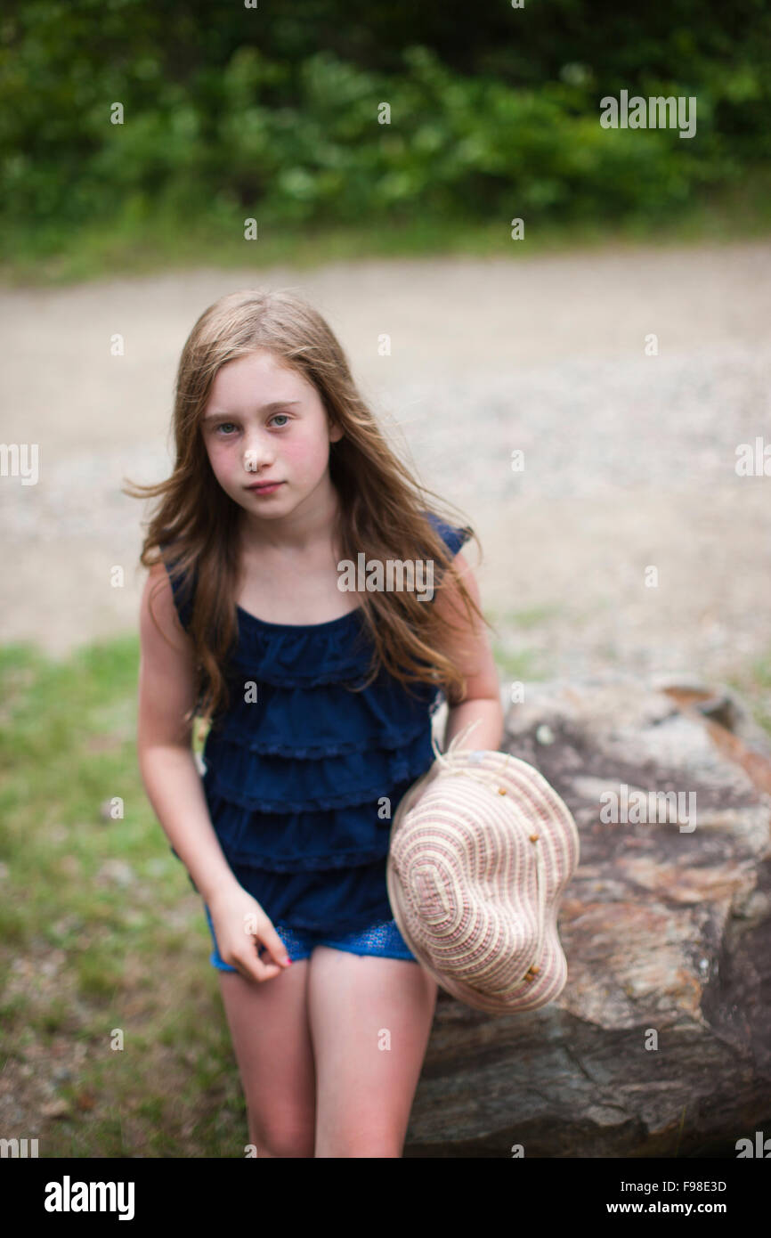 Una giovane ragazza con i capelli lunghi si appoggia contro una roccia. Foto Stock