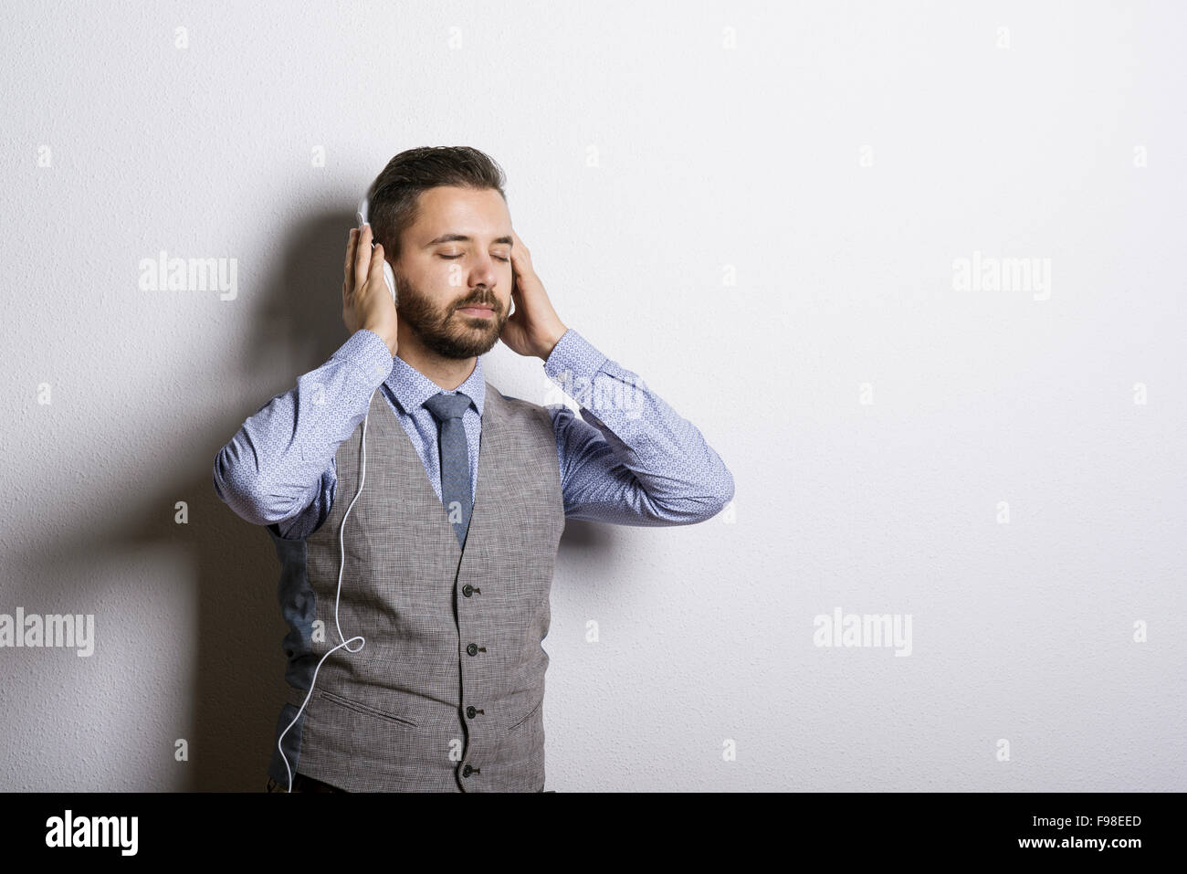 Studio shot della moderna hipster imprenditore con cuffie e ascolto di musica Foto Stock