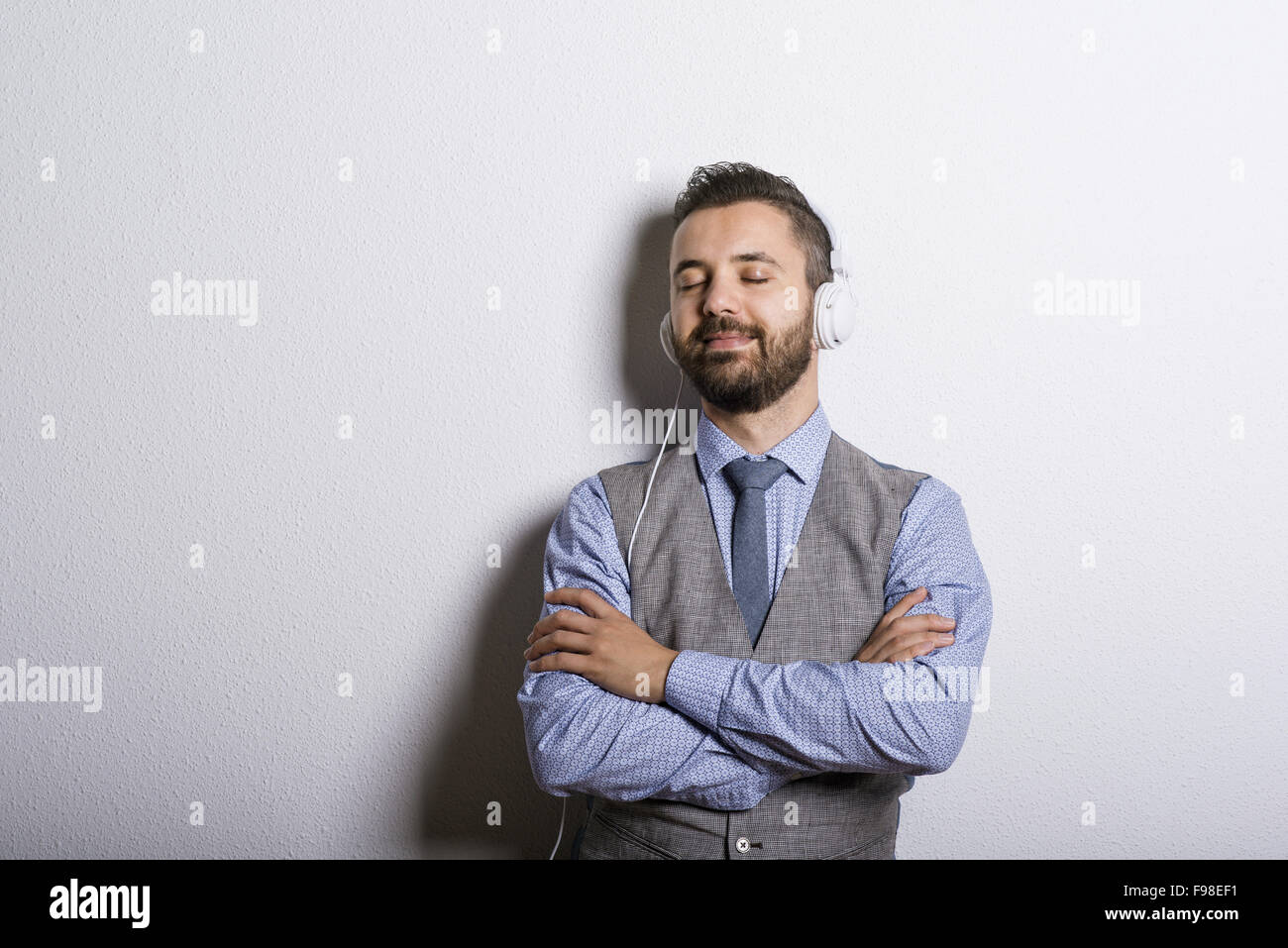 Studio shot della moderna hipster imprenditore con cuffie e ascolto di musica Foto Stock