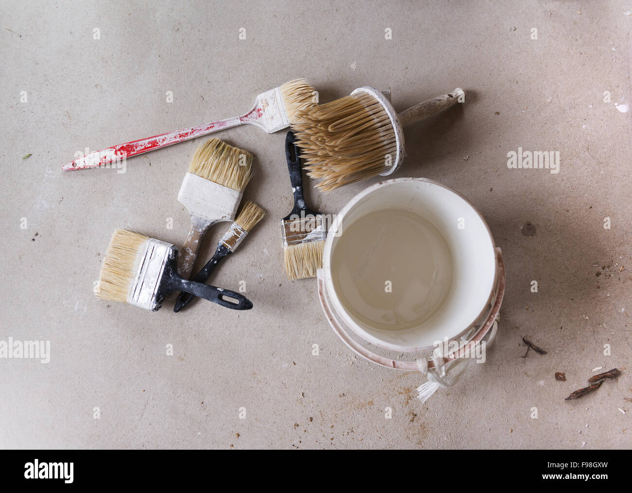 La preparazione per la verniciatura della parete. Dettaglio del pennello e secchio di colore sul pavimento. Foto Stock