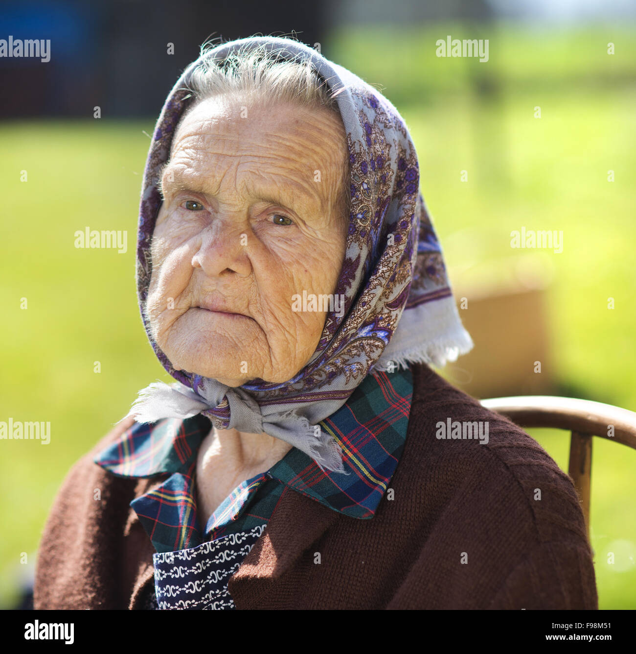 Molto vecchia donna con testa sciarpa sedersi e rilassarsi in giardino Foto  stock - Alamy
