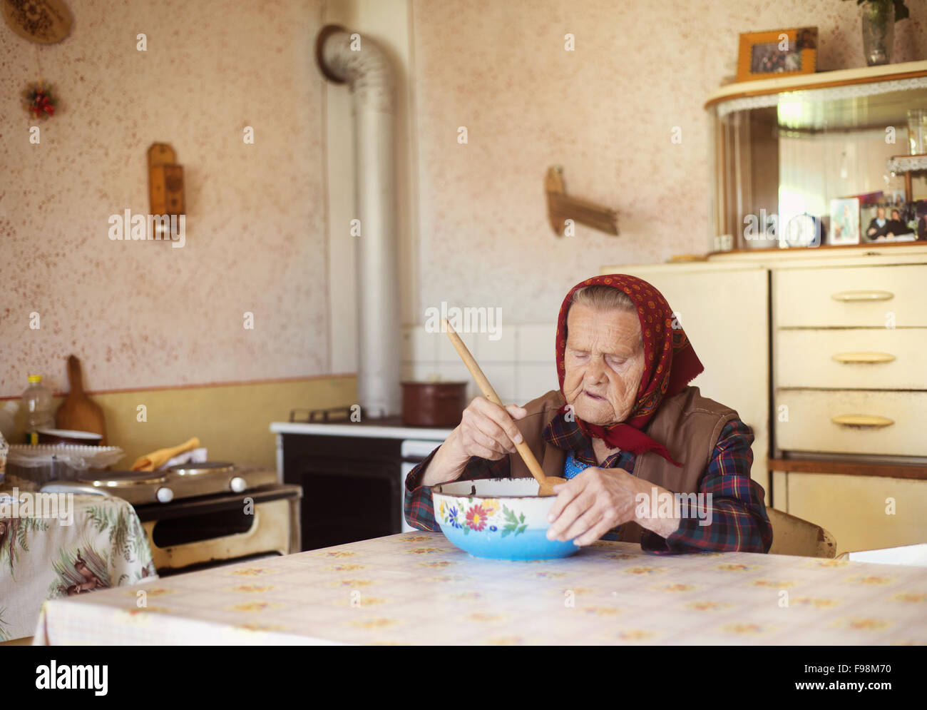 Molto vecchia donna nella preparazione degli alimenti nel suo vecchio stile country kitchen Foto Stock