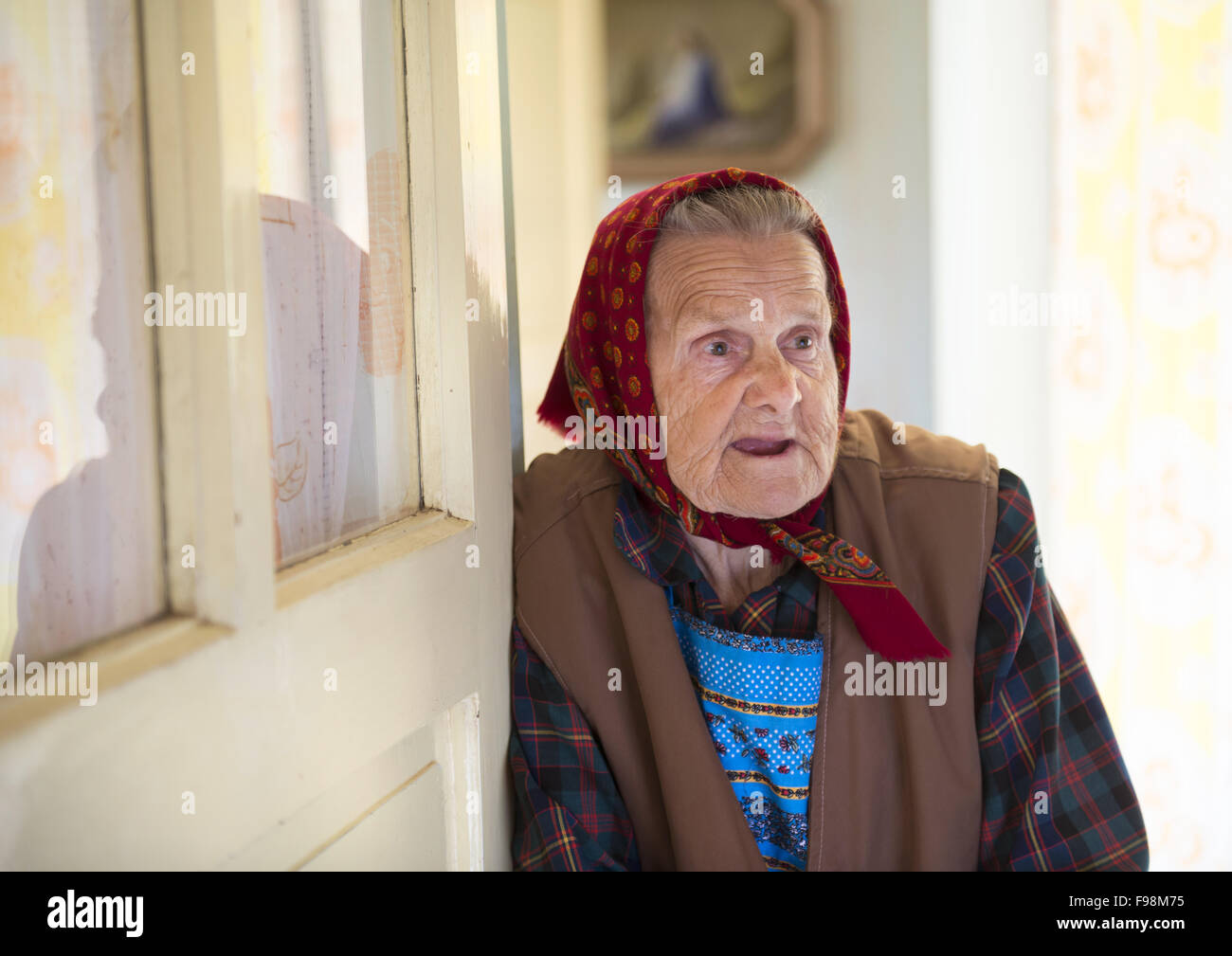 Molto vecchia donna è in piedi per la porta e guardando la telecamera al suo stile country house Foto Stock
