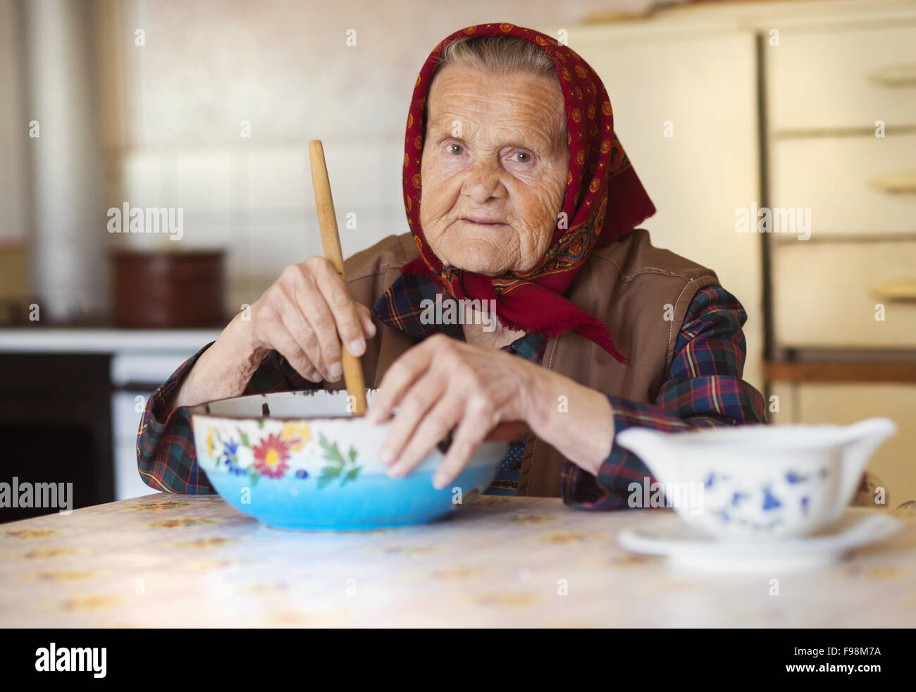 Molto vecchia donna nella preparazione degli alimenti nel suo vecchio stile country kitchen Foto Stock