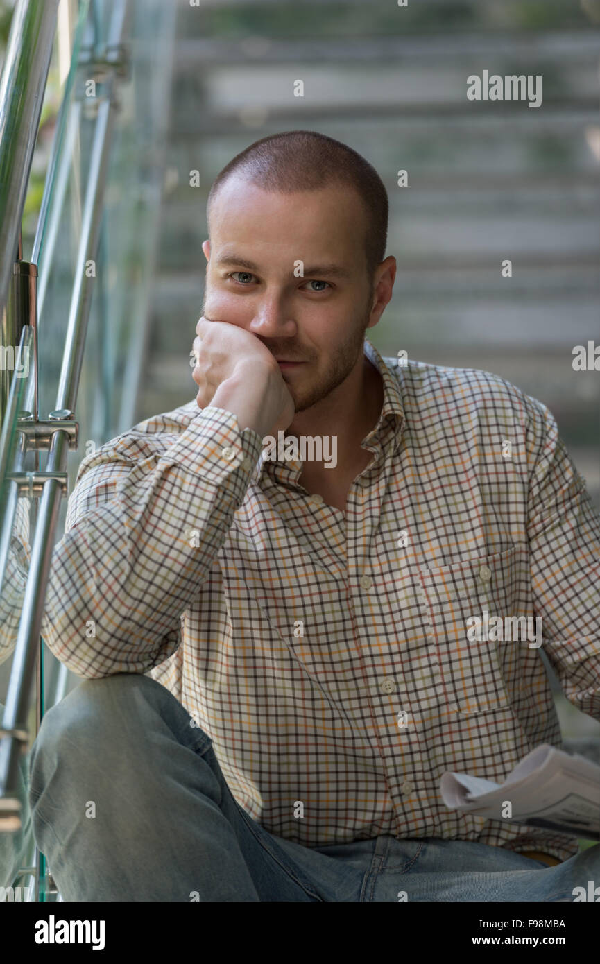 Uomo bello leggendo un giornale e di pensiero Foto Stock