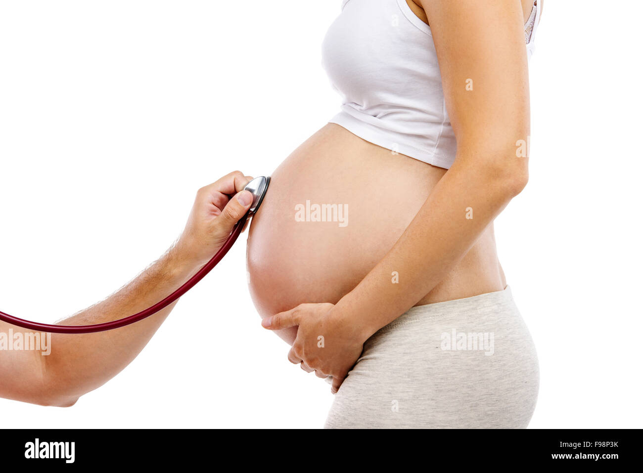 Irriconoscibile donna incinta essendo dato prenatale a controllare dal medico, isolato su sfondo bianco Foto Stock