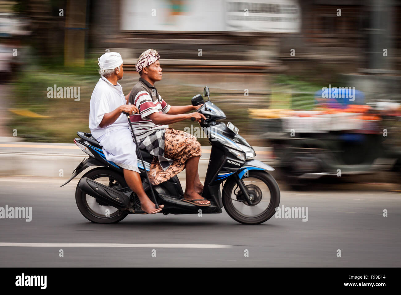 BALI, Indonesia - 27 agosto 2015: panoramica colpo di due uomini Balinese in sella a una moto in Ubud, Bali su agosto 27th, 2015. Foto Stock