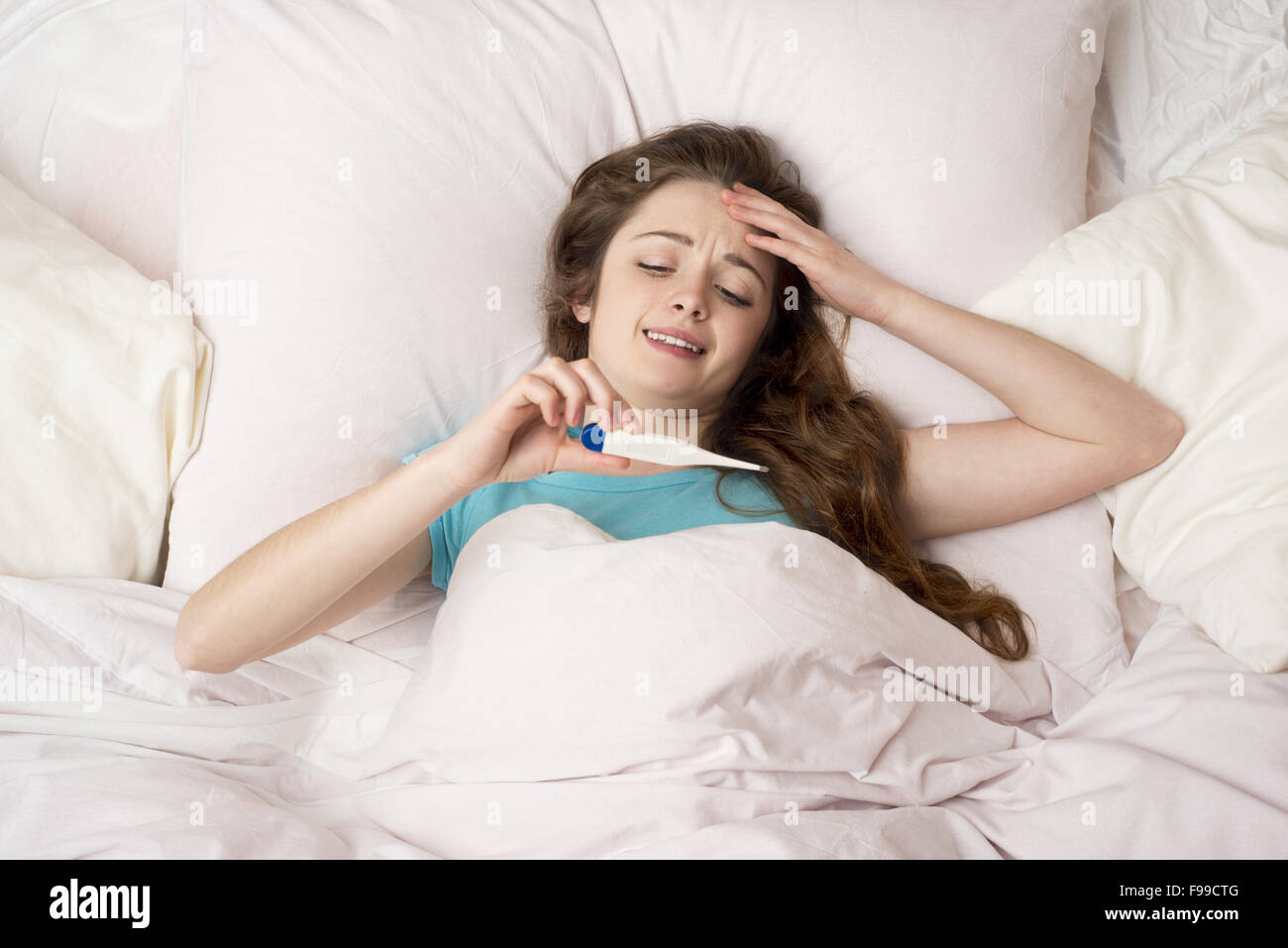 Malata con il termometro è giacente in letto. Ella ha freddo, influenza e febbre alta. Foto Stock