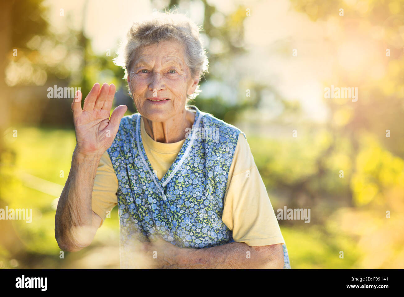 Ritratto di donna senior in grembiule nel giardino soleggiato Foto Stock