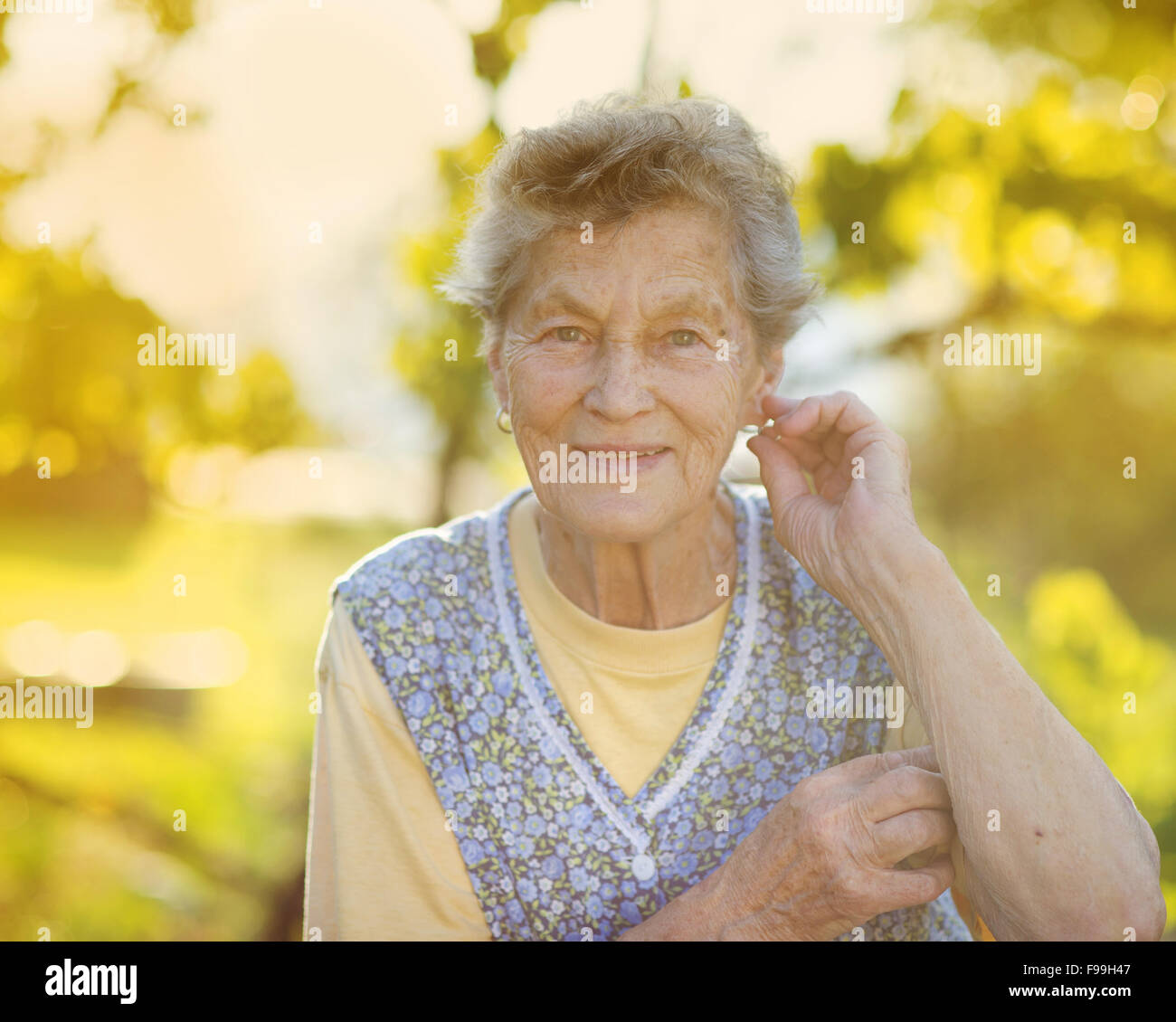 Ritratto di donna senior in grembiule nel giardino soleggiato Foto Stock