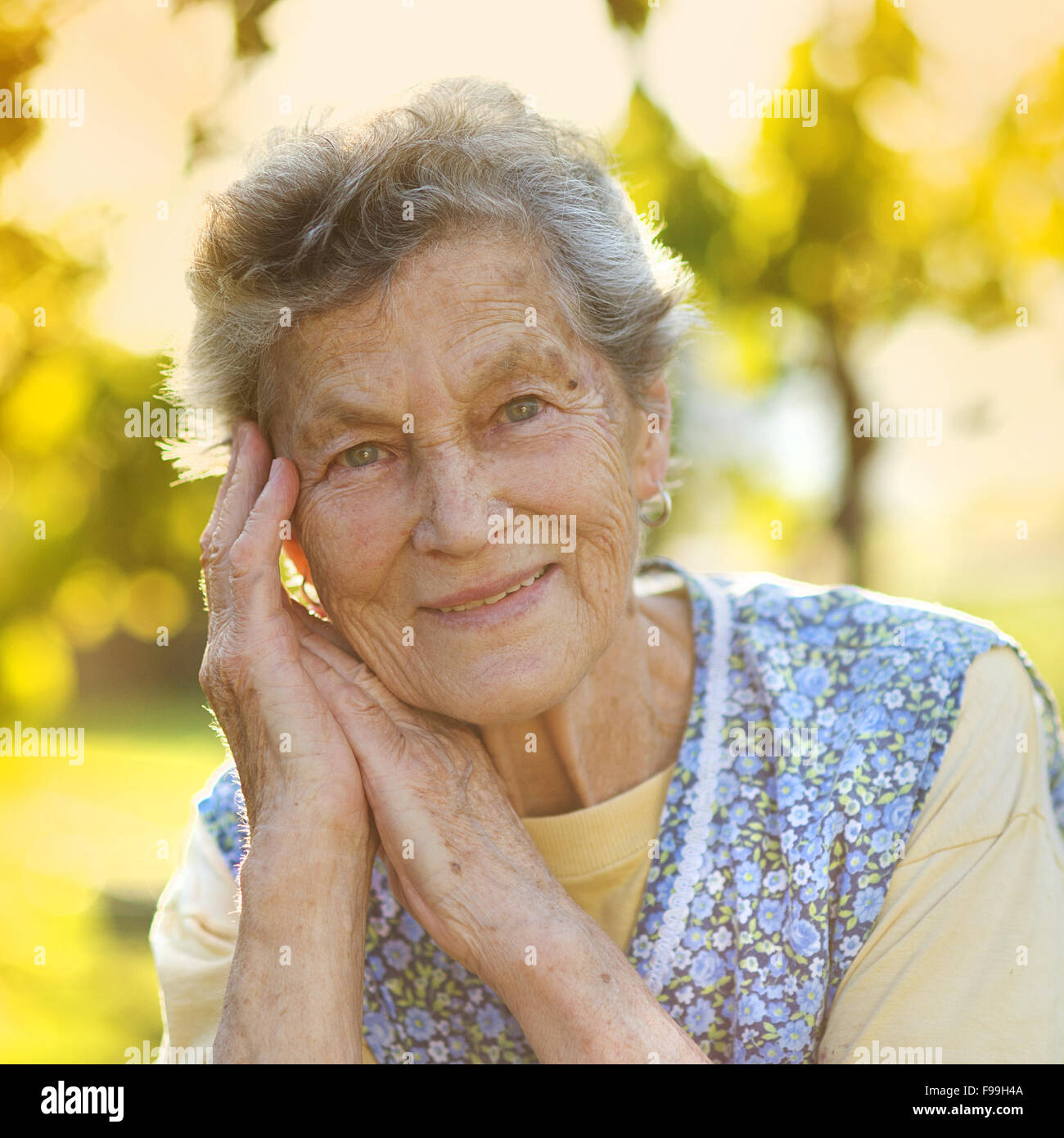 Ritratto di donna senior in grembiule nel giardino soleggiato Foto Stock