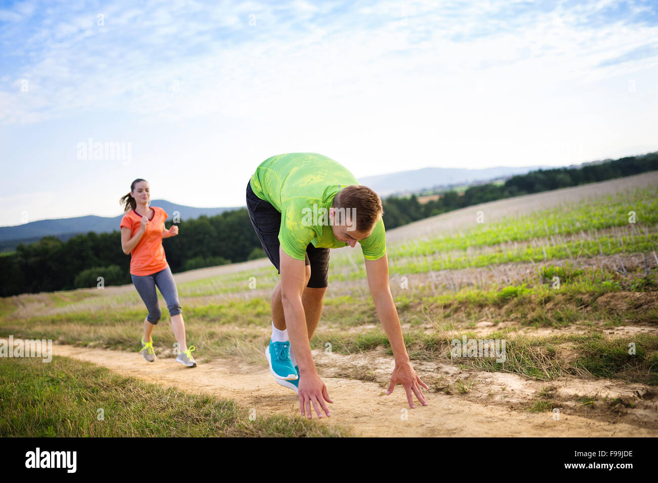 Runner maschio inciampare e cadere sul cross country trail Foto Stock