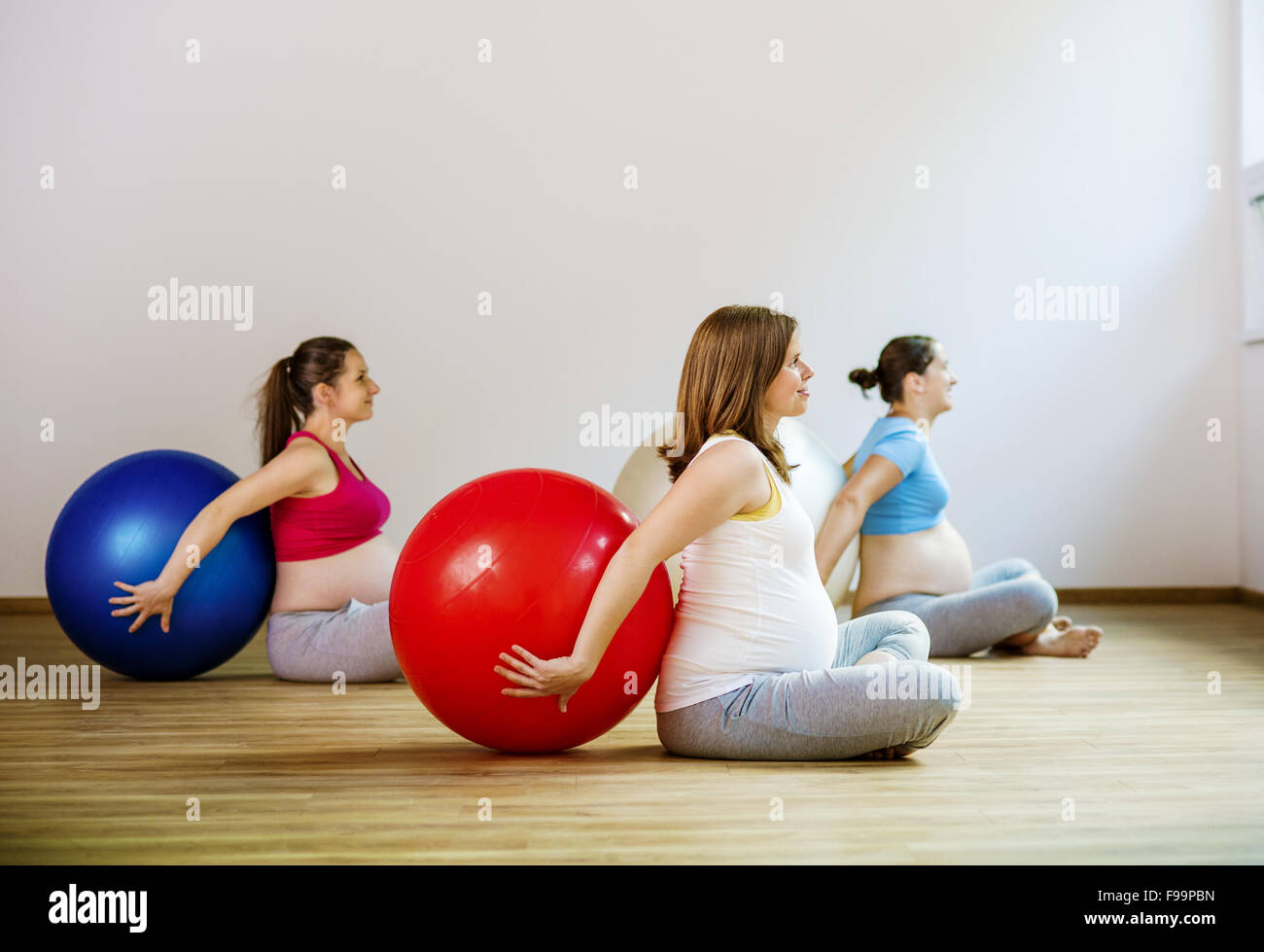 Giovani donne in stato di gravidanza facendo esercizio di rilassamento utilizzando una sfera di fitness Foto Stock