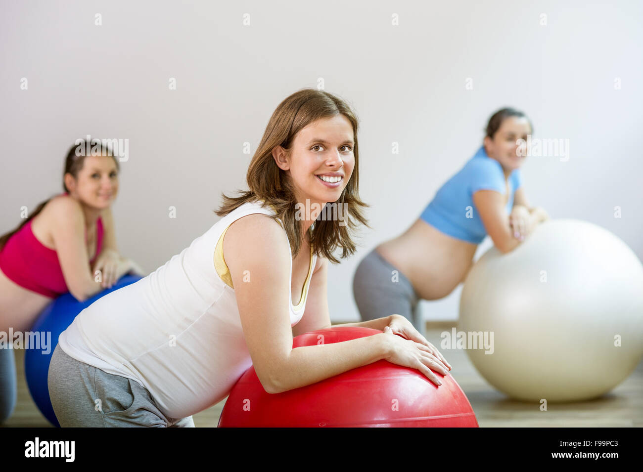 Giovani donne in stato di gravidanza facendo esercizio di rilassamento utilizzando una sfera di fitness Foto Stock