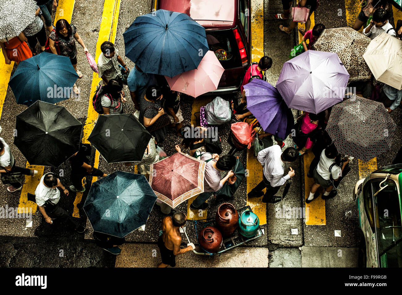 Le persone che attraversano una strada sotto la pioggia Foto Stock