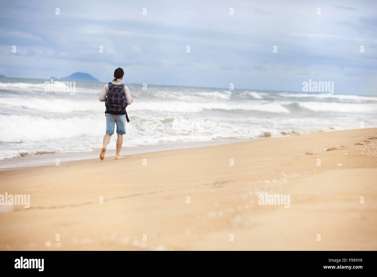 Bel giovane uomo caucasico camminare da solo con zaino sulla spiaggia Foto Stock