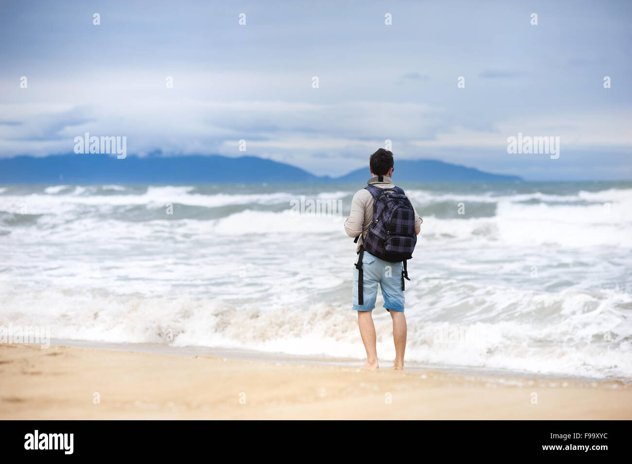Bel giovane uomo caucasico camminare da solo con zaino sulla spiaggia Foto Stock