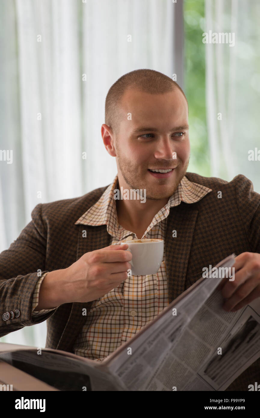 Malinconici imprenditore leggendo un giornale in cafe Foto Stock